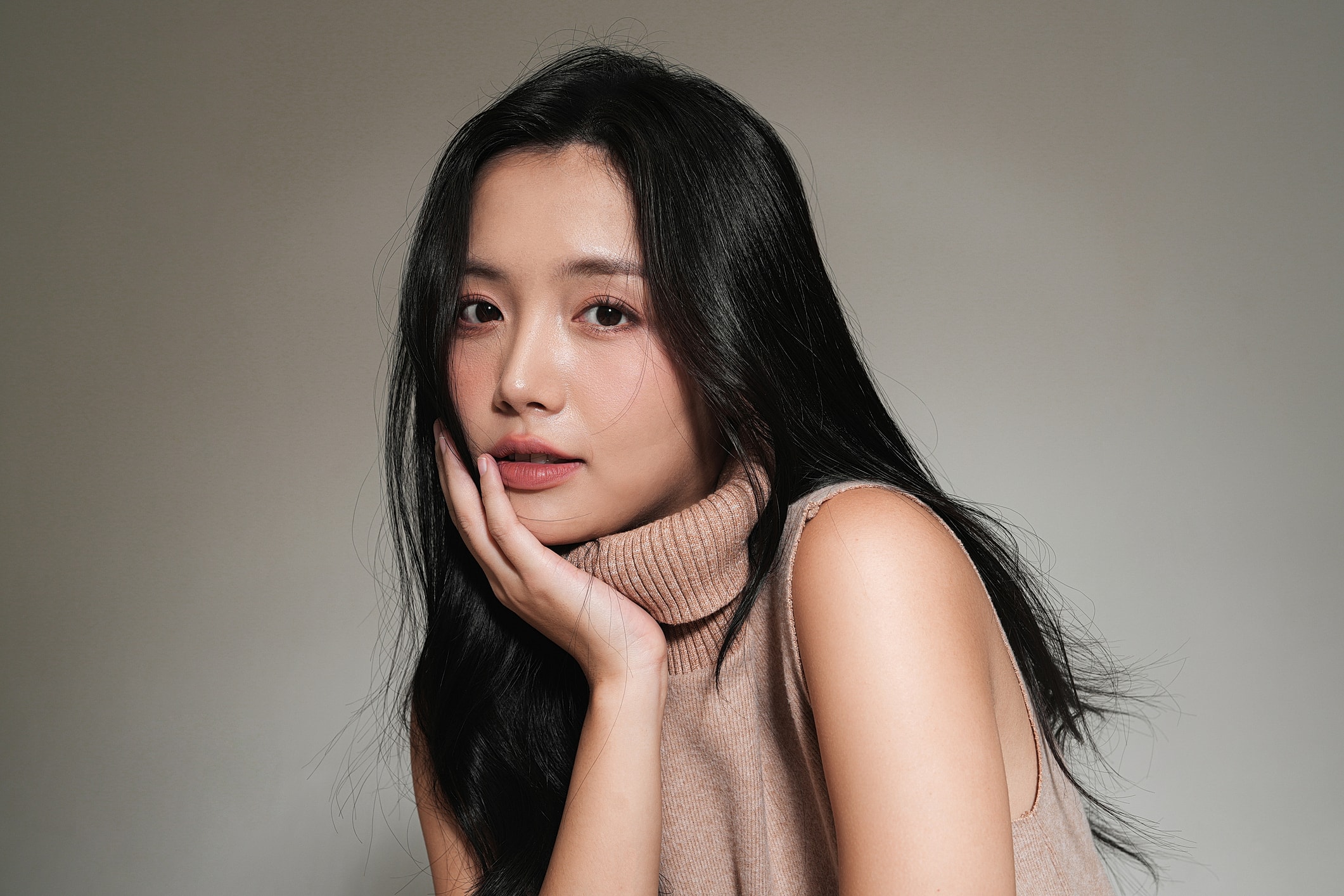 Woman with long hair resting chin on hand.